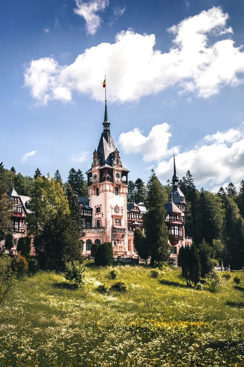 Le château de Peleș avec ses hautes flèches et sa façade à colombages face au versant boisé des Carpates au-dessus de Sinaia